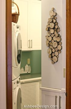 a washer and dryer in a small room with wood slices on the wall