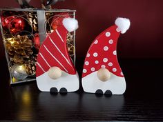 two wooden santa hats sitting on top of a table next to a box filled with ornaments