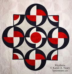 a red and black quilt with circles in the center on a white wallpaper background