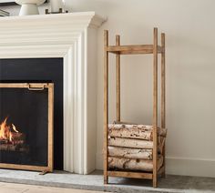 a fireplace with logs stacked on the floor next to it