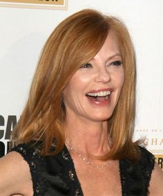 a woman with red hair smiling and wearing a black dress in front of a white wall