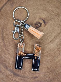 the letter h is made out of wood and has a tassel hanging from it