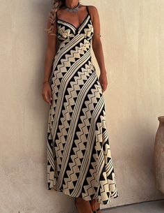 a woman standing against a wall wearing a black and white dress with geometric patterns on it