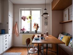 a kitchen with a table and chairs in front of a window filled with potted plants