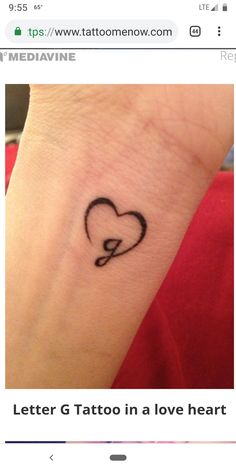 a small heart tattoo on the wrist with an arrow in it's center,