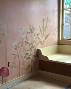 a room with pink walls and white flowers painted on the wall next to a window