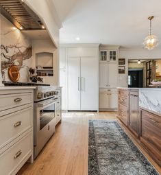 a kitchen with white cabinets and marble counter tops, wood flooring and an area rug