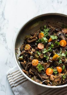 a pan filled with mushrooms and tomatoes on top of a table next to a towel