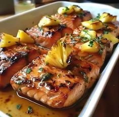 grilled salmon with pineapple and herbs in a white dish on a wooden table