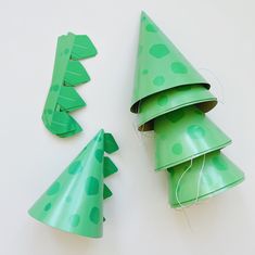 three green paper christmas trees are on the table next to each other and one is cut out