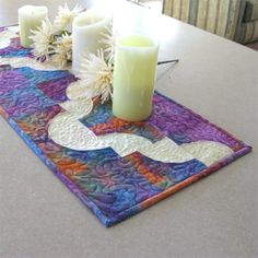 a table topped with candles and flowers on top of a wooden table covered in fabric