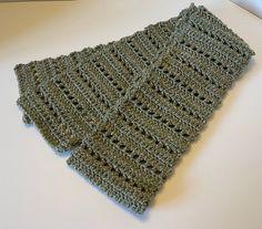 a green knitted scarf sitting on top of a table