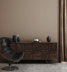 a black chair sitting in front of a wooden cabinet with vases on top of it