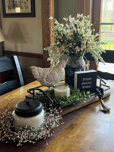 a wooden table topped with a vase filled with flowers and a bird figurine