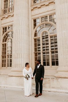 a bride and groom standing in front of a large building