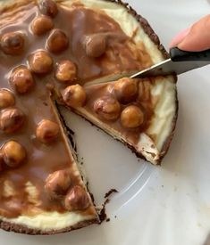 someone is cutting into a chocolate cheesecake with nuts on the top and filling in the middle