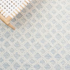 a white chair sitting on top of a wooden floor next to a rug covered in blue and white patterns