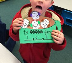 a young boy is holding up a sign that says the cocoa farm with sheeps on it