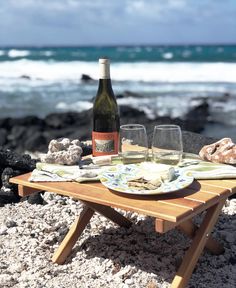 a bottle of wine sitting on top of a wooden table next to a plate with food