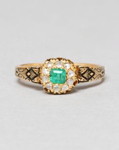 an antique emerald and diamond ring, possibly from the early 20th century in yellow gold