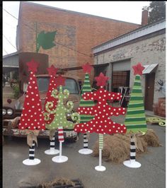 several christmas trees are on display in front of an old truck and other junk yard decorations