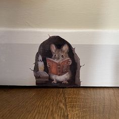 a mouse reading a book while sitting in a hole on the floor next to a wall