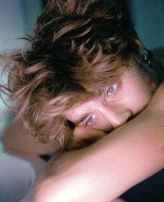 a young man is laying down with his head resting on the edge of a toilet