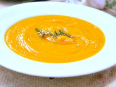 a white bowl filled with carrot soup on top of a table