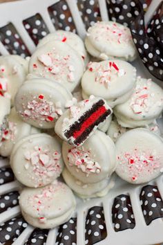 a white plate topped with lots of red and white cake bites covered in frosting