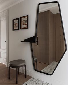 a mirror hanging on the wall next to a stool