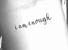 the word i am enough written in cursive writing on a woman's stomach