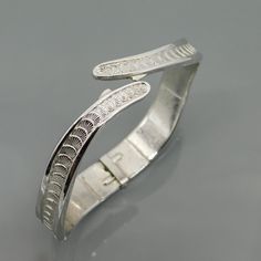 Vintage Monet bangle bracelet is silver tone metal with a bypass design. This hinged bangle has a unique design with a wider bottom and slowly tapering near the top with the bypass. At the base it is about 1/2 inch wide and each side of the bypass is 1/8 inch at the very tip. The bracelet is a sort of rounded square rather than a typical bracelet that is round. The highlight is the overlapping shell like design that runs all the way around the bangle. Bracelet is about 6 1/2 inches wearable leng Adjustable Silver Bangle With Oyster Bracelet, Silver Hinged Bracelets For Weddings, Silver Hinged Bangle For Wedding, Silver Hinged Bracelet For Wedding, Nickel-free Silver Bangle Cuff Bracelet, Hinged Sterling Silver Bangle In Silver, Silver Hinged Bangle As Gift, Silver Hinged Metal Bracelets, Silver Hinged Bracelet As A Gift