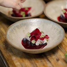 three bowls filled with food on top of a wooden table