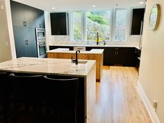 an empty kitchen with black cabinets and white counter tops