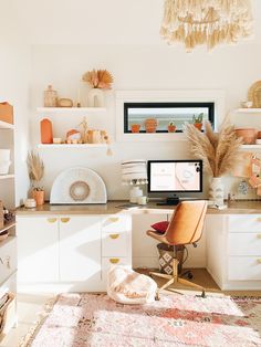 a desk with a computer on top of it in a room filled with shelves and furniture