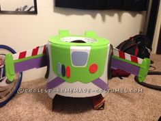 a green and purple toy plane sitting on top of a floor next to a wall