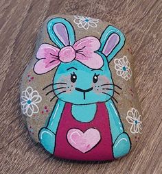 a painted rock with an image of a bunny holding a heart on it's chest