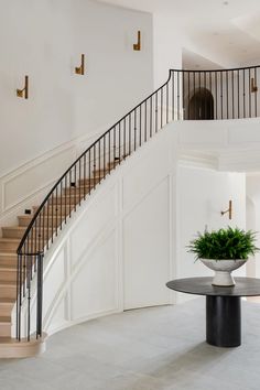 there is a plant in a vase on the table next to the stairs and railings