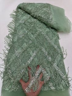 a person's hand holding onto a green shawl