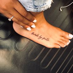 a woman's foot with a tattoo that reads, walk by faith