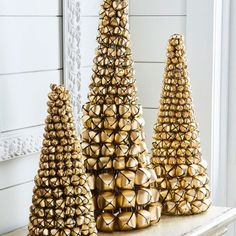 three gold christmas trees sitting on top of a mantle