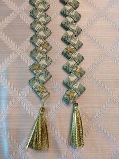 two stacks of money with tassels hanging from it's sides on a wall