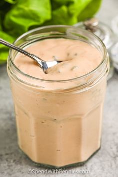 a spoon in a jar filled with peanut butter and lettuce on the side