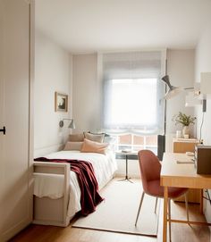 a bedroom with a bed, desk and chair in the corner next to a window