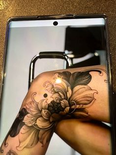 a woman's leg with flowers on it and a mirror in the back ground