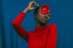 a woman in a red shirt holding a flower on her head