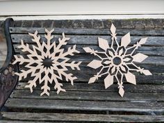 two wooden snowflakes sitting on top of a bench