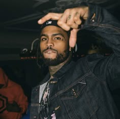 a man wearing a denim jacket and tie with his hand on the top of his head