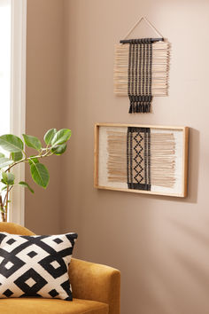 a living room with two wall hangings on the wall and a plant next to it