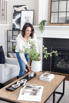 a woman is holding a potted plant in front of a coffee table with rocks on it